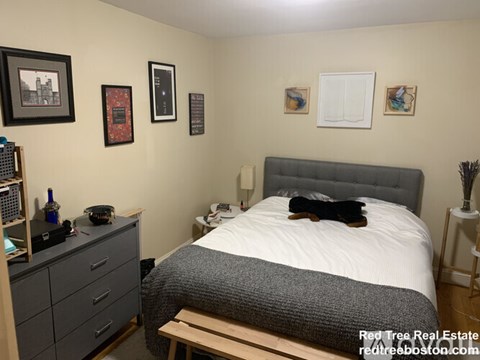 A bedroom with a bed, nightstand, and a wooden bench.