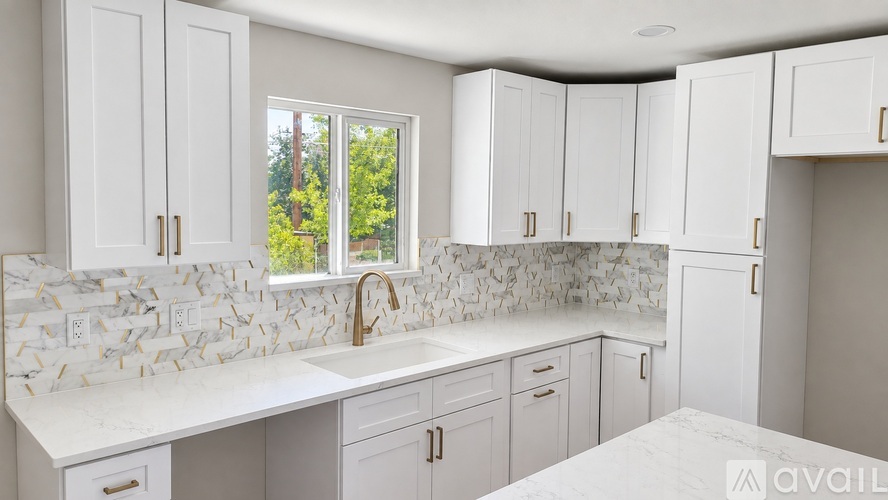 A kitchen with white cabinets and a marble backsplash.