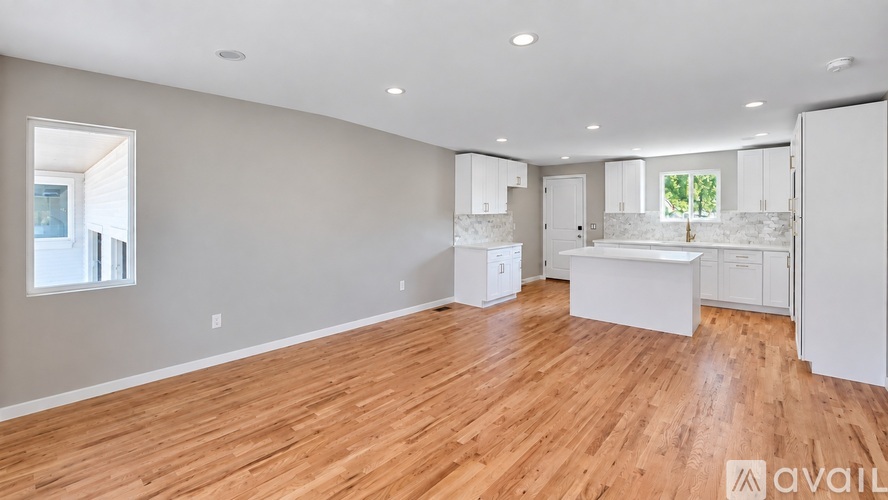 A spacious room with wooden floors and white walls.