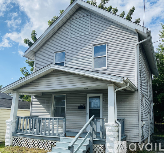 A house with a grey siding and a porch with a railing.