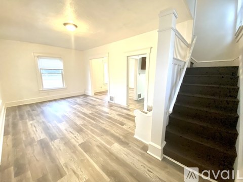 A room with wooden floors and a staircase leading to another room.