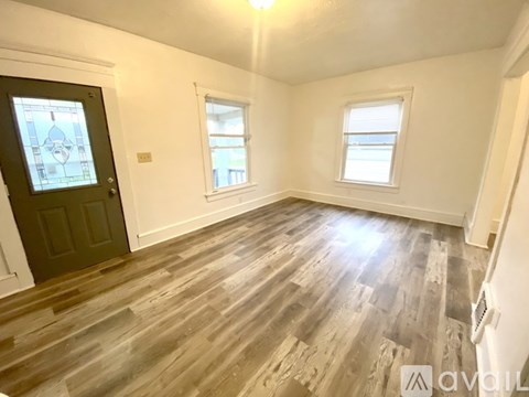 A room with wooden flooring and a black door with a stained glass window.