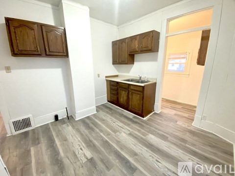 A kitchen area with wooden cabinets and a white wall.