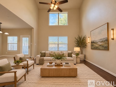 A living room with a ceiling fan, couches, and a painting on the wall.