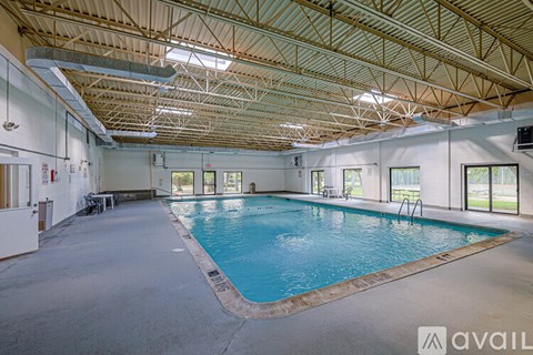 A large indoor swimming pool in a spacious room with a high ceiling and large windows.