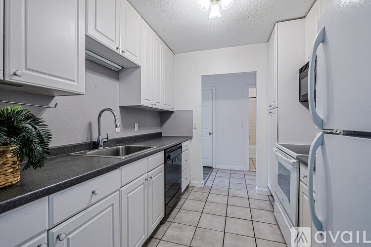 A kitchen with white cabinets and a black countertop.