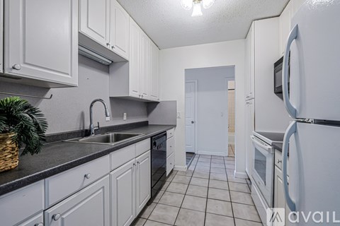 A kitchen with white cabinets and a black countertop.