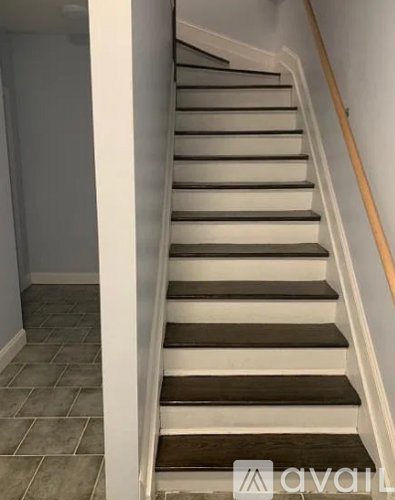A staircase with a wooden handrail and tiled steps.