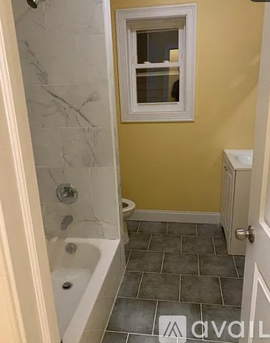 A bathroom with a tub, toilet, and window.