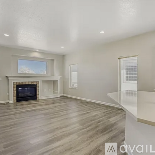 A spacious living room with a fireplace and a large window.