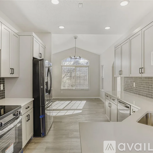A kitchen with white cabinets and a black refrigerator.