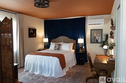 A bedroom with a large bed and a wooden chair.