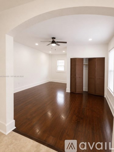 A spacious room with wooden floors and a ceiling fan.