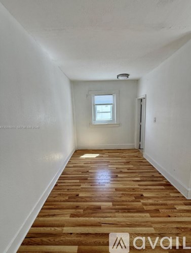 A long hallway with wooden floors and white walls.