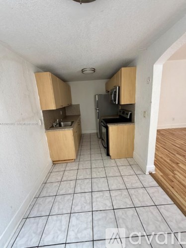 A kitchen with white tiled floors and wooden cabinets.
