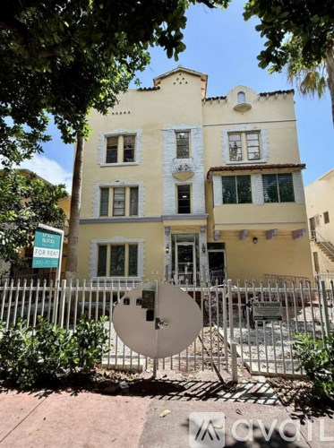 A yellow building with a satellite dish in front.