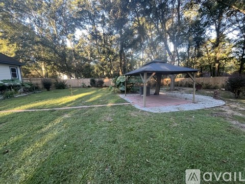 A gazebo is situated in the middle of a grassy backyard.