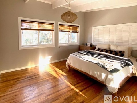 A bedroom with a large bed and wooden floors.
