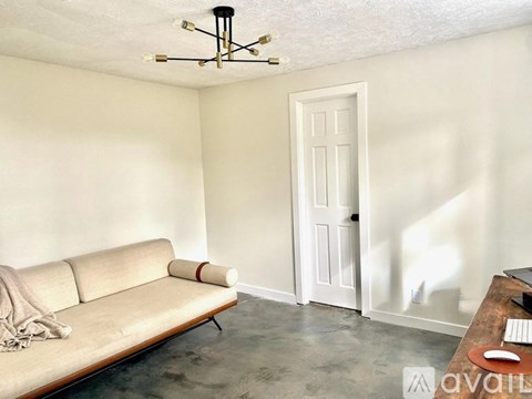 A living room with a couch, a coffee table, and a door.