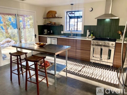 A kitchen with a table and two stools in front of a stove.