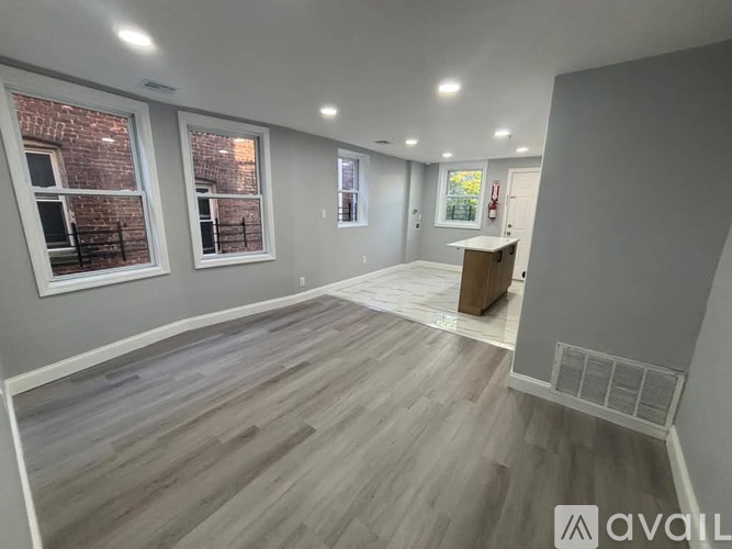A room with wooden flooring and a brick wall visible through the windows.