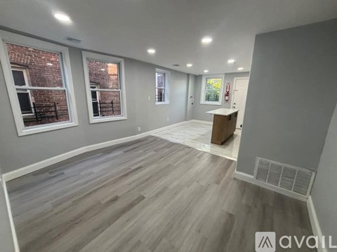 A room with wooden flooring and a brick wall visible through the windows.