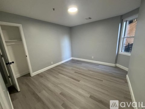 A room with wooden flooring and a door on the left.