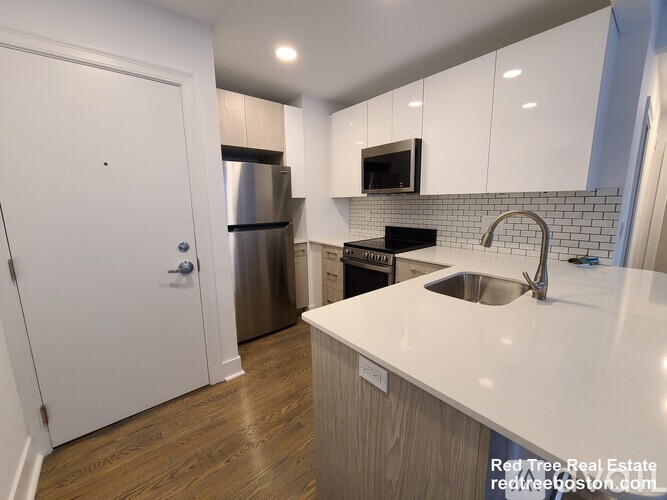 A kitchen with white cabinets and a stainless steel refrigerator.