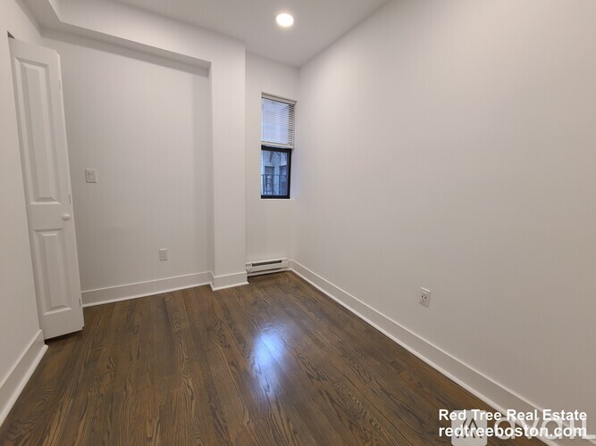 A room with wooden flooring and white walls.