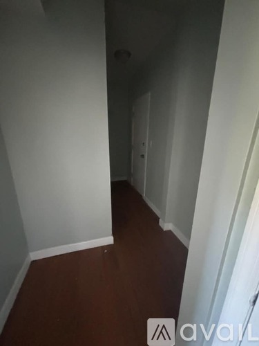 A long hallway with white walls and wood flooring.