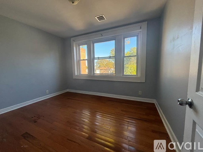A room with wooden flooring and a large window.