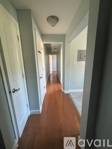 A long hallway with wood floors and white walls.