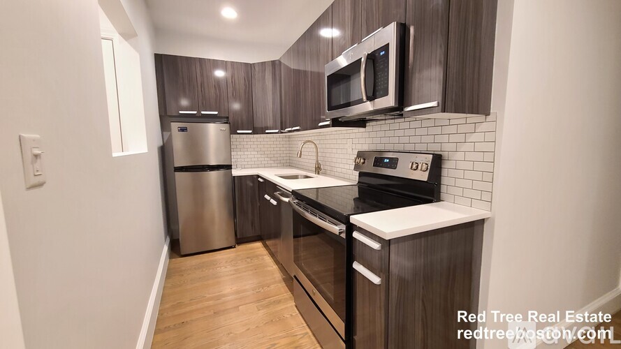 A kitchen with a stainless steel refrigerator and a microwave above the stove.