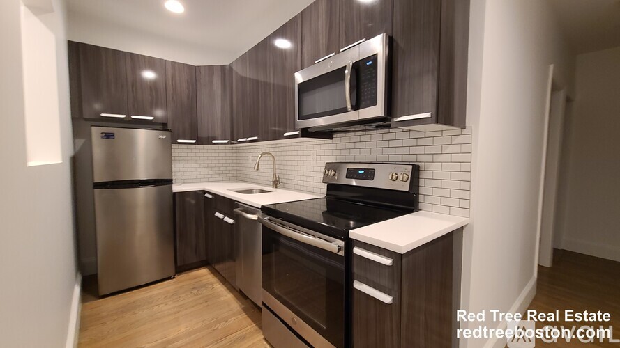 A modern kitchen with dark wood cabinets and stainless steel appliances.