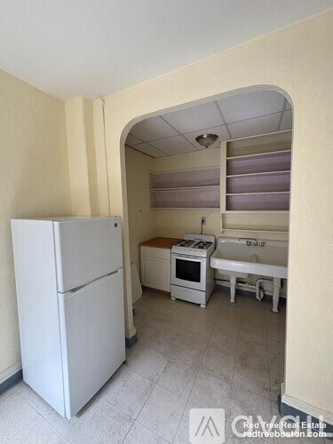 A kitchen with a white refrigerator, a white oven, and a white sink.