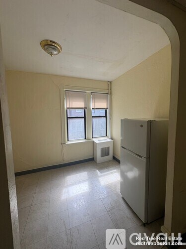A room with a window and a refrigerator.