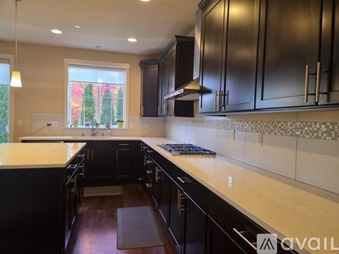 A kitchen with black cabinets and a checkered backsplash.