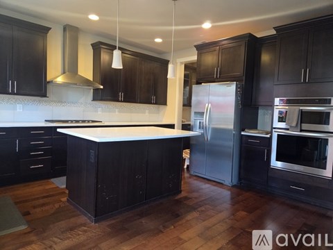A kitchen with black cabinets and a white island.