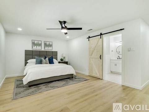 A bedroom with a bed, a ceiling fan, and a rug on the floor.
