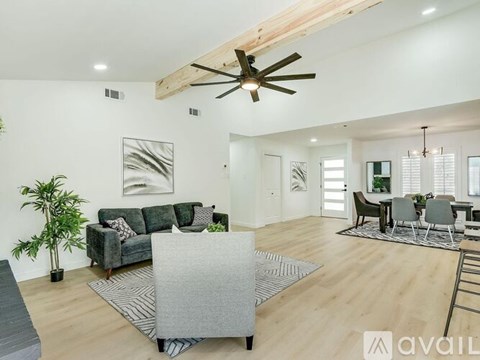A living room with a grey couch and a wooden ceiling fan.