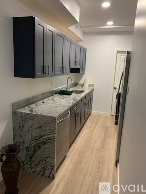 A kitchen with marble countertops and black cabinets.