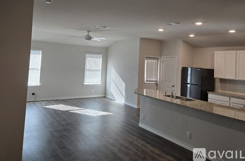 A spacious kitchen with a black fridge and white cabinets.