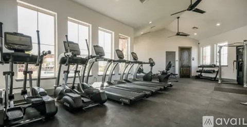 A gym with treadmills, elliptical machines, and a fan.