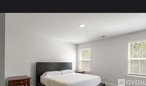 A bedroom with a bed, nightstand, and window.