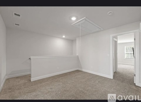 A spacious, empty room with carpeted floor and white walls.