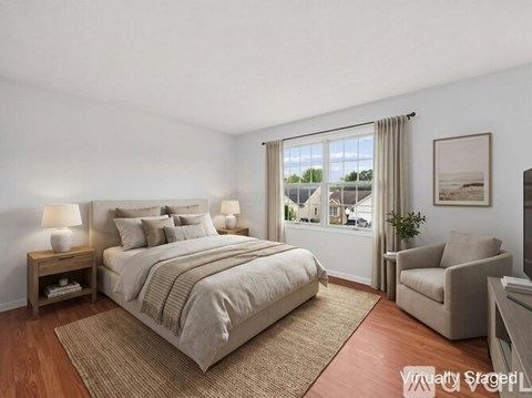 A bedroom with a large bed and a window overlooking a residential area.