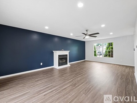 A spacious room with a fireplace and a ceiling fan.