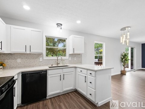 A kitchen with white cabinets and a black dishwasher.