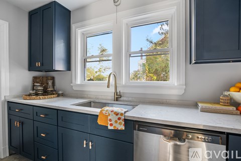 A kitchen with dark blue cabinets and a stainless steel dishwasher.