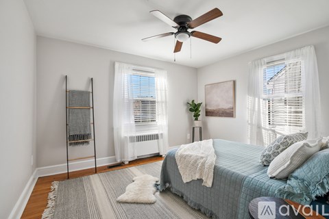 A bedroom with a bed, a fan, and a window with curtains.
